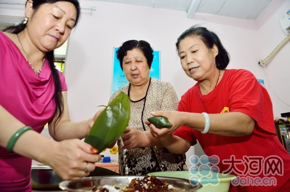 　　志愿者在进行包“爱心粽子”大比拼