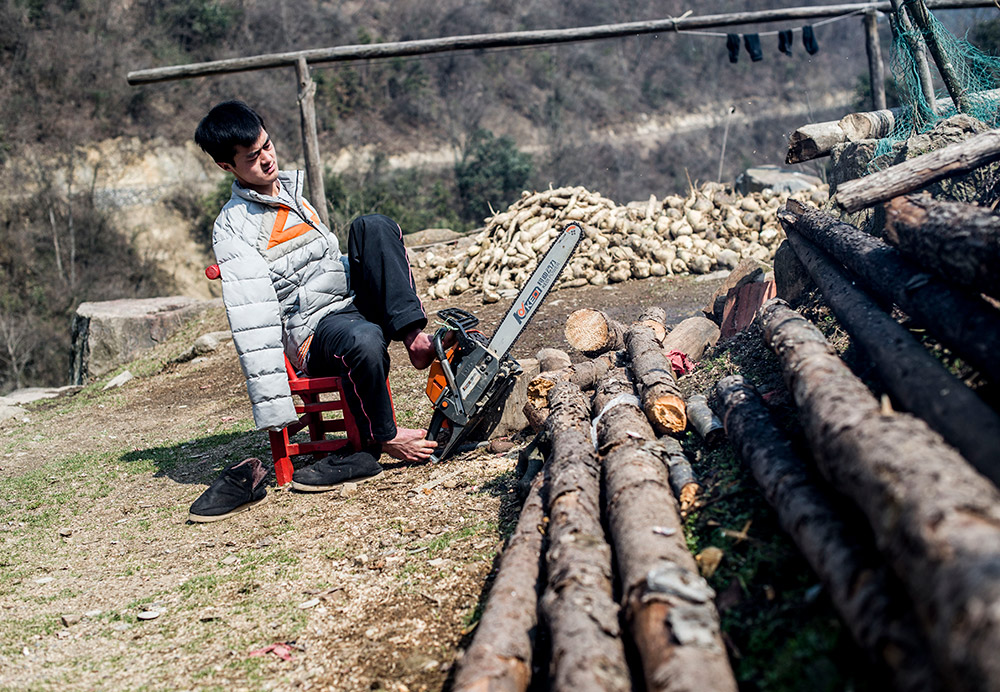 陈兹方在家中用油锯锯柴（3月2日摄）。