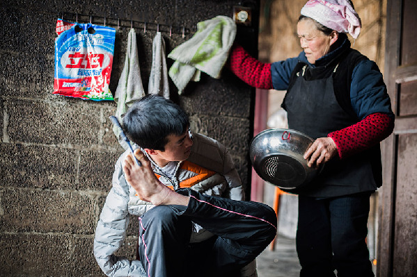 陈兹方（左）在家中梳理头发准备与客户约谈，母亲在一旁准备为他做早饭（3月2日摄）。
