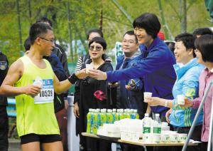 郎平在补给站为参赛运动员送水。记者　胡龙召　摄