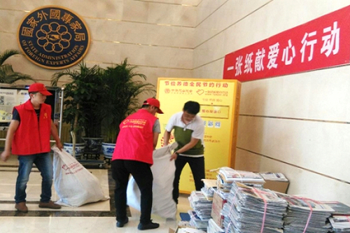 4、工作人员帮助志愿者打包废旧报纸
