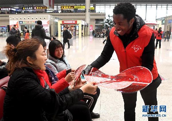 2月6日，一位外籍志愿者在郑州东站向旅客分发“福”字。新华社记者李安摄