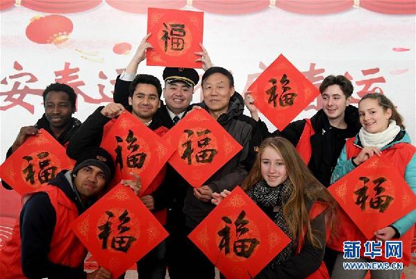 2月6日，外籍志愿者和车站工作人员、书法爱好者一起展示书写的“福”字，向旅客拜年。新华社记者李安摄