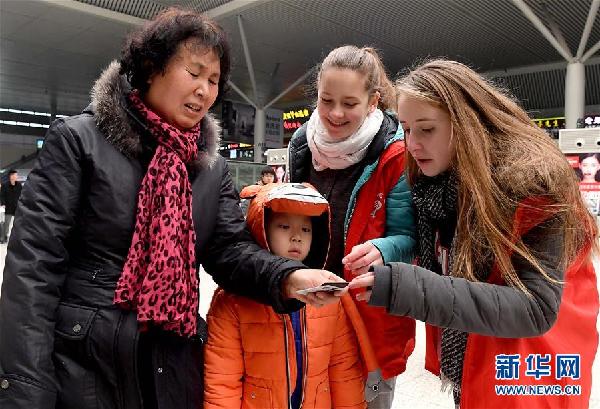 2月6日，来自德国的志愿者李米（右一）、静远（右二）帮助旅客查看票面信息指引检票口位置。